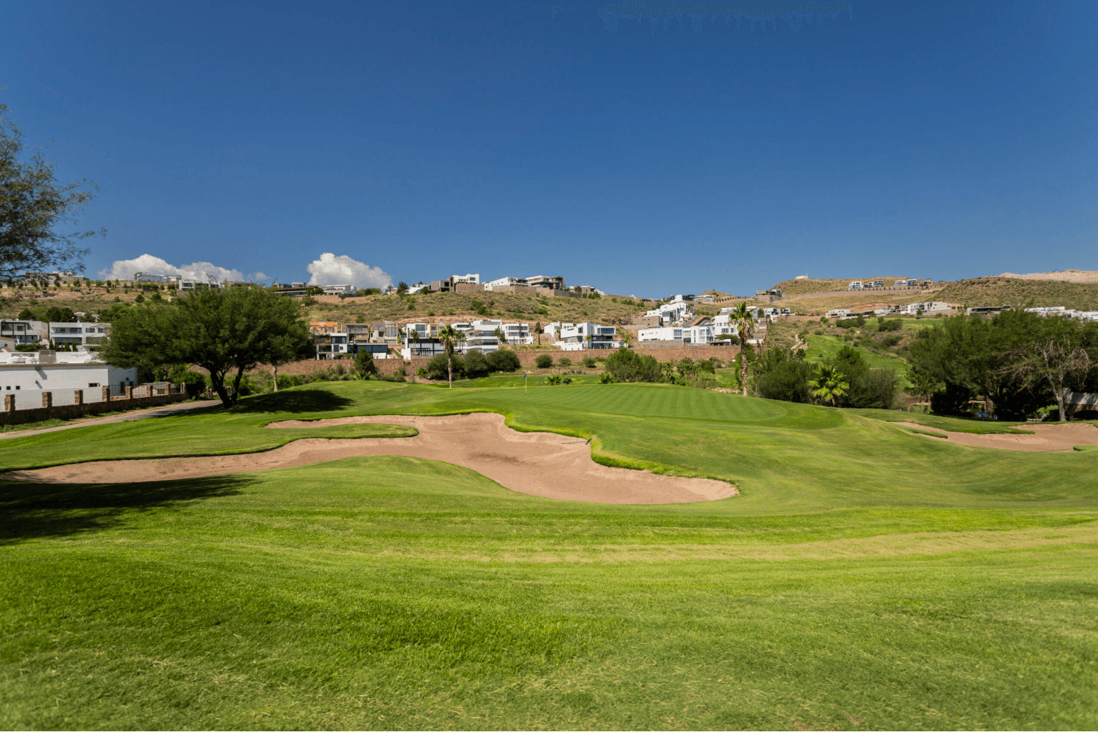 Vista del campo de golf con bunkers y residencial